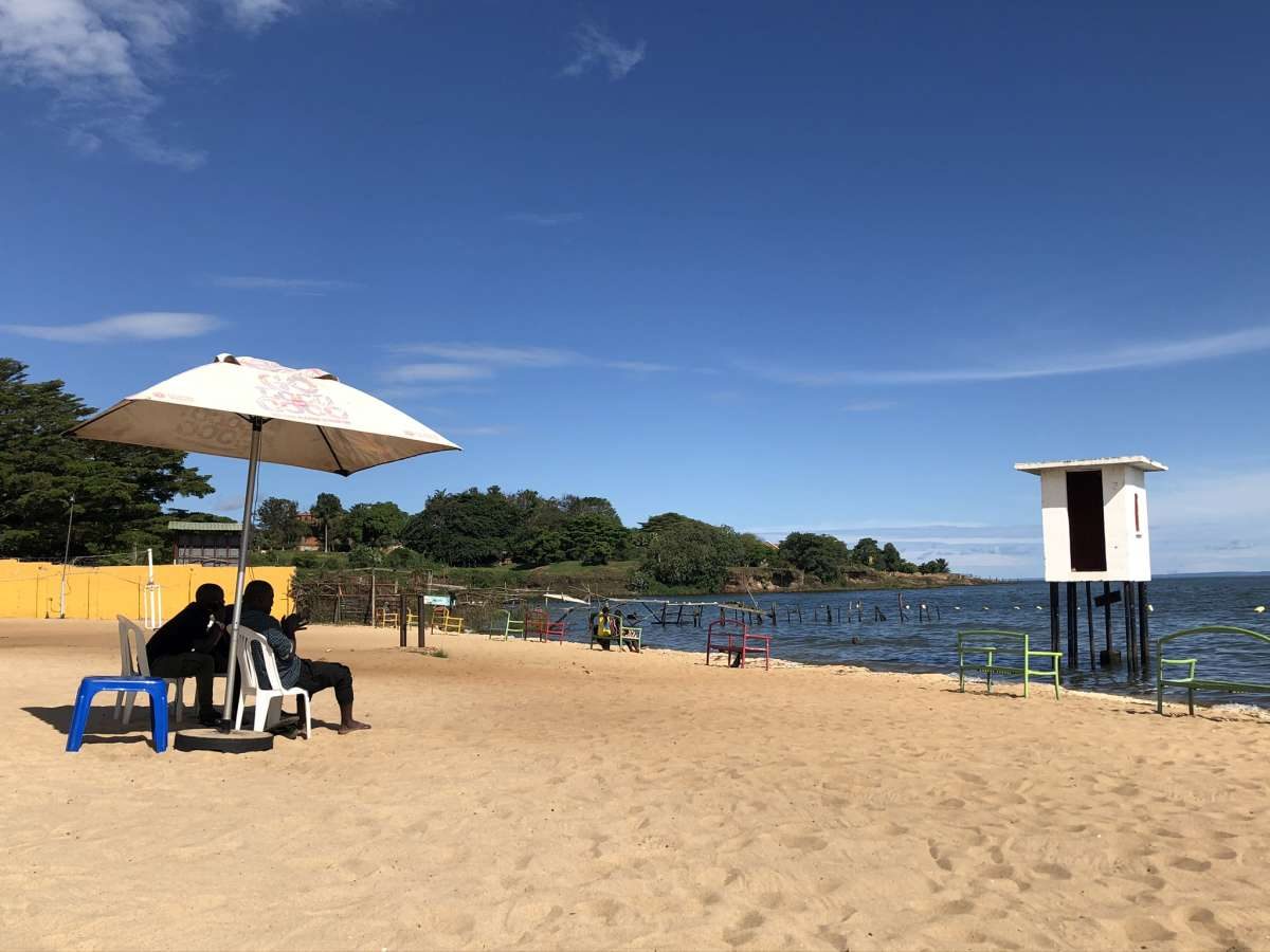 Sandy beach on Lake Victoria with a shade umbrella and calm blue water