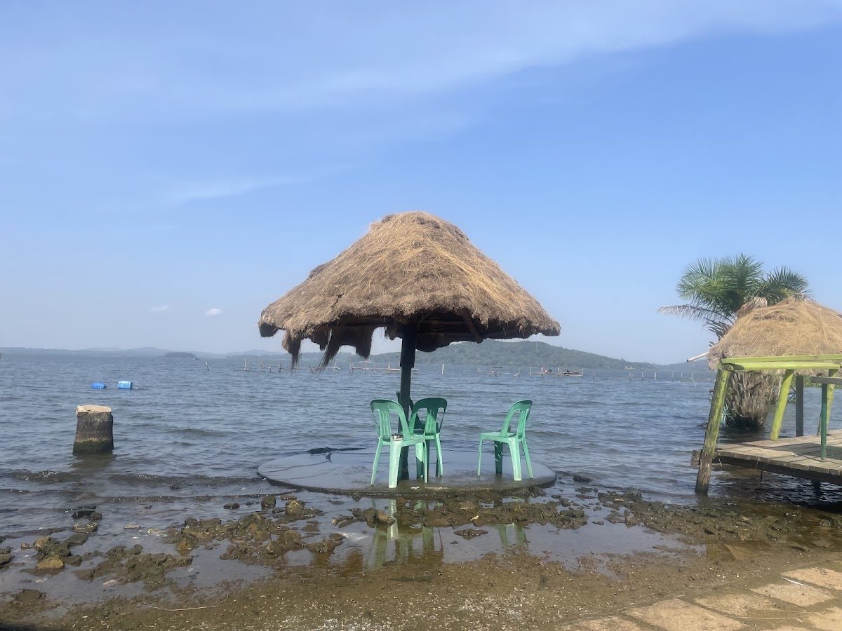 Thatched umbrella with green chairs on a platform over Lake Victoria at KK Resort Beach