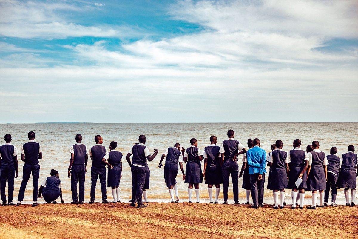 Group of friends standing at the edge of a wide sandy lake shore under a big sky